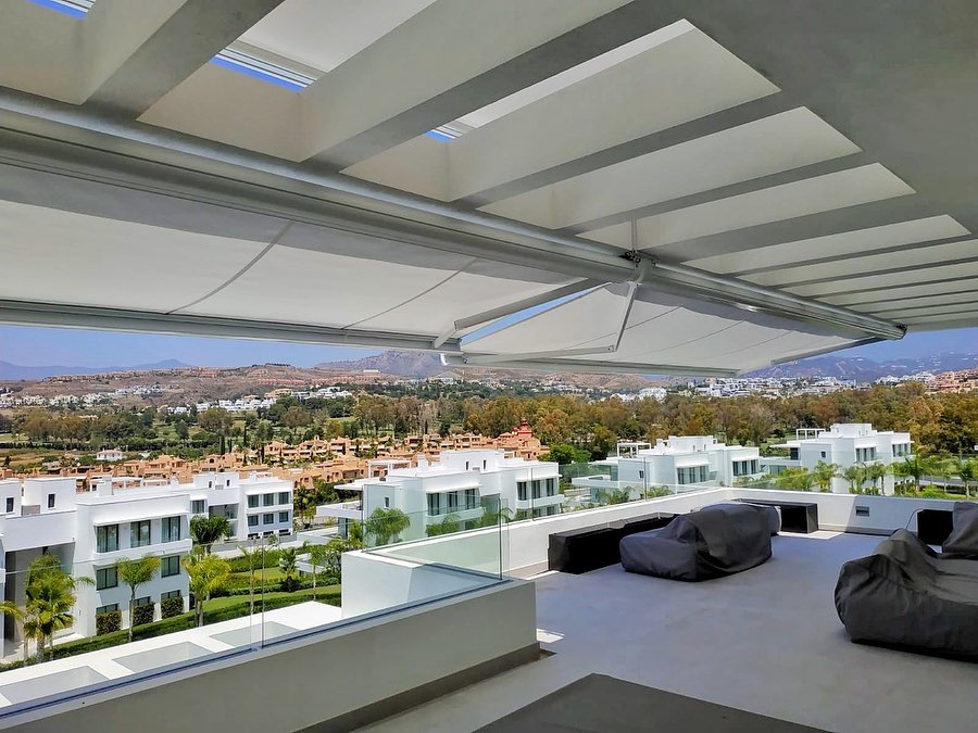 Amplio toldo retráctil proporciona sombra en una terraza moderna con vista panorámica.