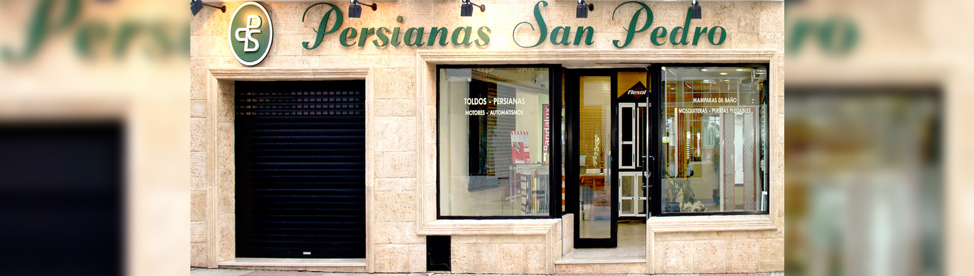 Fachada de tienda "Persianas San Pedro" con un escaparate que muestra varios modelos de persianas y toldos, y una entrada abierta al público.