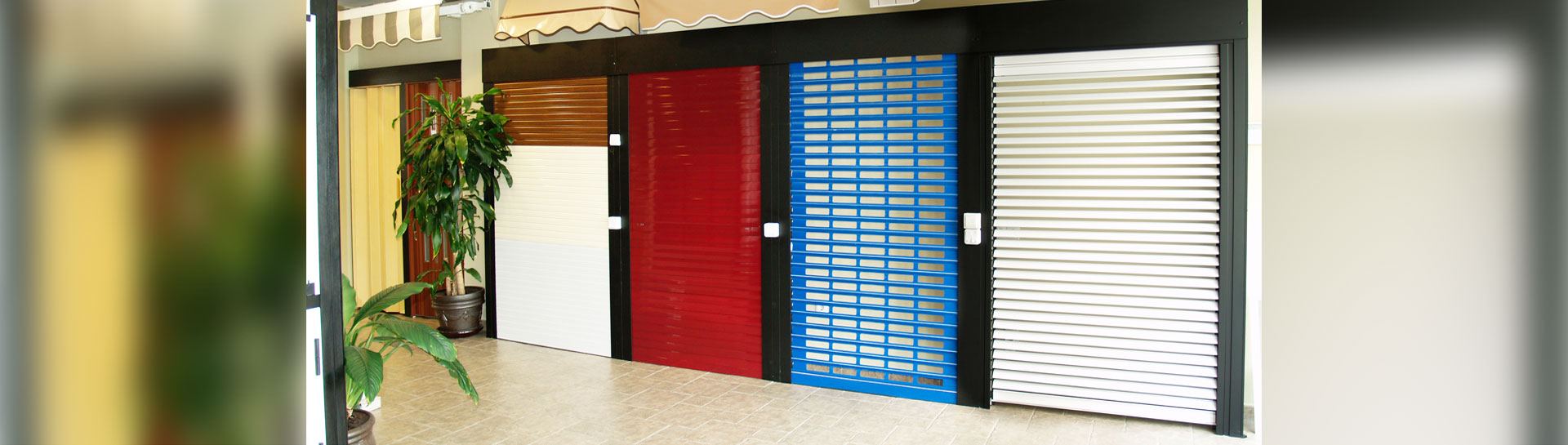Variedad de persianas de seguridad en diferentes colores mostradas en una exposición comercial.